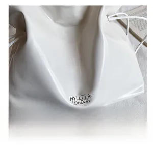 Gros plan du sac cabas en cuir brillant blanc avec cordon et lettrage de la marque