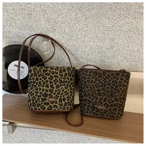 Detail of leopard print bucket bags with leather straps and branding on wooden shelf