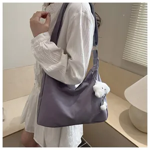 Purple crescent shoulder bag featuring a cute white plush puppy charm and minimal text