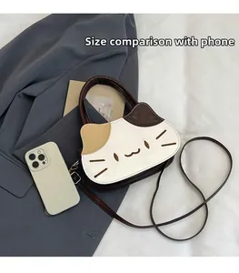Cat-shaped crossbody bag shown next to a smartphone for an accurate size comparison