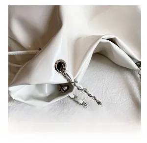 Détail du sac cabas en cuir blanc avec bandoulière en chaîne argentée et œillets métal