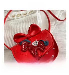 Détail du sac enfant rouge matelassé avec nœud papillon et patch poney tressé chic