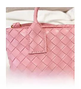 Macro detail of the woven pink leather texture and gold hardware on the bucket bag