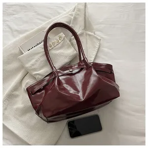 Detailed view of dark red wax leather tote bag with elegant pleats and metal buckle