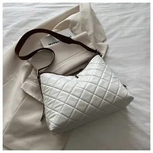 Detail of white quilted hobo bag with diamond stitching and dark brown shoulder strap