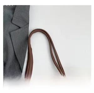 Detail view of the white leather tote bag featuring comfortable dark brown rolled handles