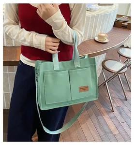 Detail of mint green canvas tote bag featuring double front pockets and leather brand tag