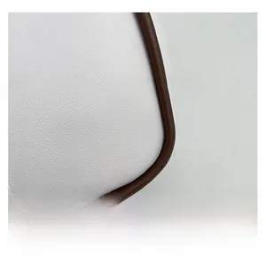 Macro view of white pebble leather tote bag with brown edge piping and stitching