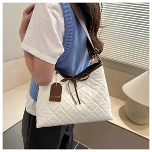 Detail of white quilted tote bag featuring a brown ribbon bow and fashion hanging tag
