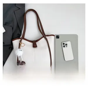 Capacity demonstration of cream tote bag holding a tablet and phone with plush charm