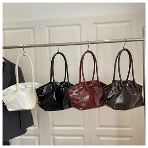 Detail of four vintage wax leather tote bags with metal bows on a metal rack