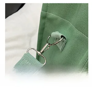 Detailed close-up of high-quality silver metal hook and thick canvas strap on green tote