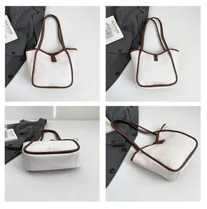 Detail view of cream leather tote bag showing slim brown handles and contrast trim details