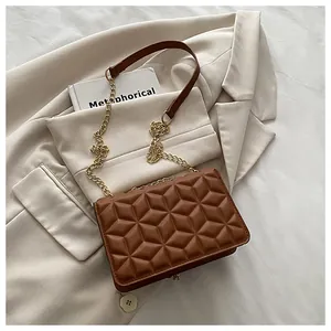 Detailed view of brown quilted crossbody bag with gold chain strap on beige blazer background