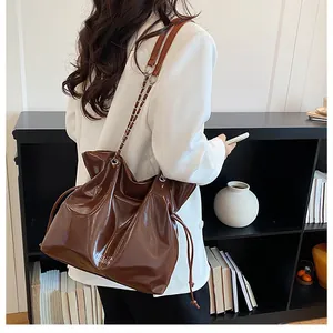 Détail du sac cabas en cuir marron brillant avec lettrage de marque blanc et chaîne fine