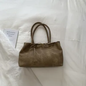 Detail of vintage brown tote bag with matte texture, dual straps and vertical stitching