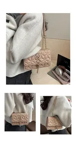 Detail of apricot shoulder bag featuring geometric embossed texture and gold S-shaped clasp