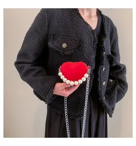Dettaglio della borsa a tracolla rossa a forma di cuore con manico di perle e catena