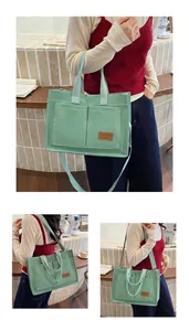 Detail of light green canvas tote bag featuring front pockets and brown leather brand patch