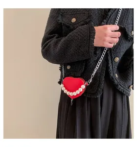 Dettaglio borsa a tracolla a cuore rossa con perle bianche e catena d'argento su modella