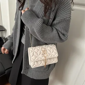 Chic beige quilted crossbody bag with gold chain strap and fringe tassel on a model