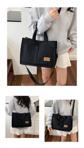 Detail of black canvas tote bag showing fashion label and adjustable shoulder strap