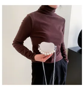 Dettaglio mini borsa bianca a cuore con manico di perle grandi e catena sottile argento