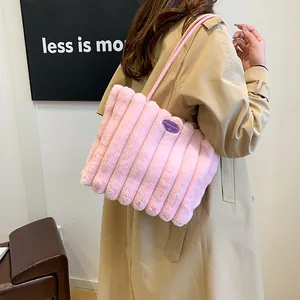 Sac fourre-tout en peluche rose à rayures et broderie porté par un mannequin en trench