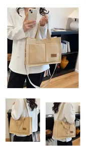 Detail of beige canvas tote bag showing dual front pockets and brown leather logo patch
