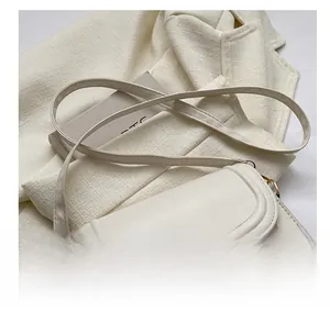 Détail du sac bandoulière crème minimaliste avec coutures doubles et sangle réglable