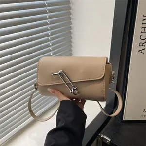 Sac baguette beige cylindrique minimaliste avec boucle en forme de grande épingle