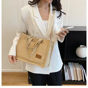 Detail of beige canvas tote bag with adjustable strap and leather logo for women