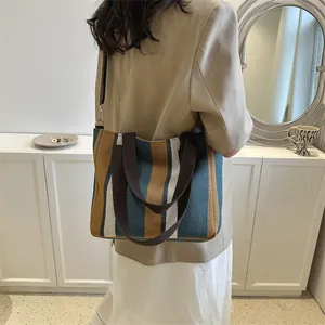 Large striped canvas tote bag in blue, yellow, and white with brown handles for women