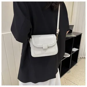 Détail du sac bandoulière minimaliste en cuir crème avec sangle réglable et boucle dorée