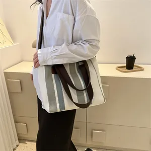 Minimalist striped canvas tote bag with brown handles and adjustable shoulder strap