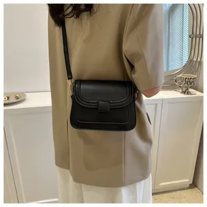 Détail d'un sac à bandoulière en cuir noir avec crochets en métal doré et rabat rectangulaire