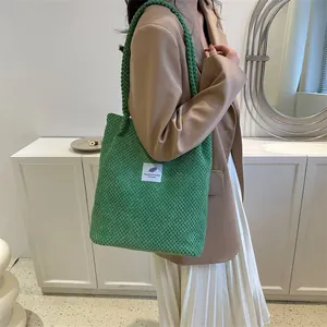 Green knit tote bag with minimalist white label shown in a stylish commute lifestyle shot