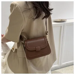 Détail rapproché du sac carré marron foncé vintage avec bandoulière dorée réglable