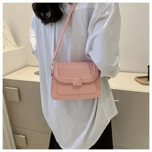 Sac bandoulière carré rose avec détails dorés et fermeture à rabat sur mannequin