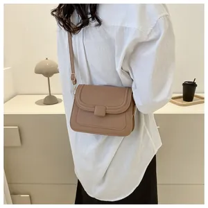 Sac bandoulière carré en cuir PU marron porté par un mannequin dans une chambre sobre