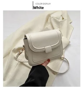 Détail d'un petit sac carré blanc minimaliste avec des boucles métalliques dorées