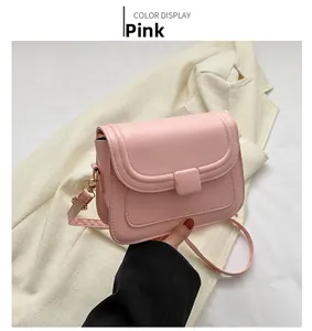 Détail d'un sac à bandoulière rose minimaliste avec rabat incurvé et bouton-pression carré