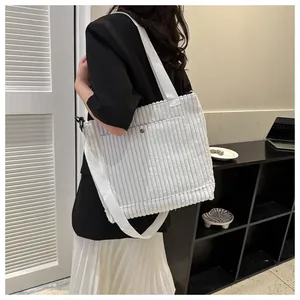 Dettaglio della borsa tote in velluto a coste bianco con manici larghi e bottone argento