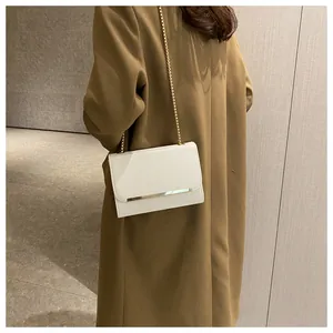 White leather square crossbody bag with gold chain strap and metal bar detail