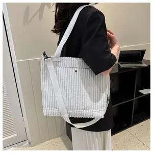 Dettaglio di una borsa tote in velluto a coste beige con trama verticale e bottone argento
