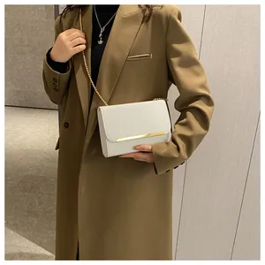 Close-up of white crossbody bag with gold chain strap on a model in a khaki blazer