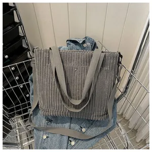 Dettaglio di una borsa tote in velluto a coste grigio con doppi manici e tracolla