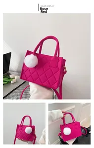 Detail der rosaroten gesteppten Filzhandtasche mit weißem Plüschball und Tragegriffen