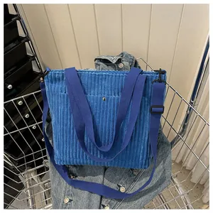 Dettaglio della borsa tote in velluto blu con tasca con fibbia e tracolla regolabile