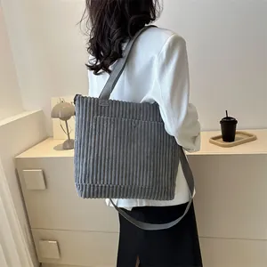 Borsa tote minimalista in velluto a coste grigio indossata a tracolla da una modella